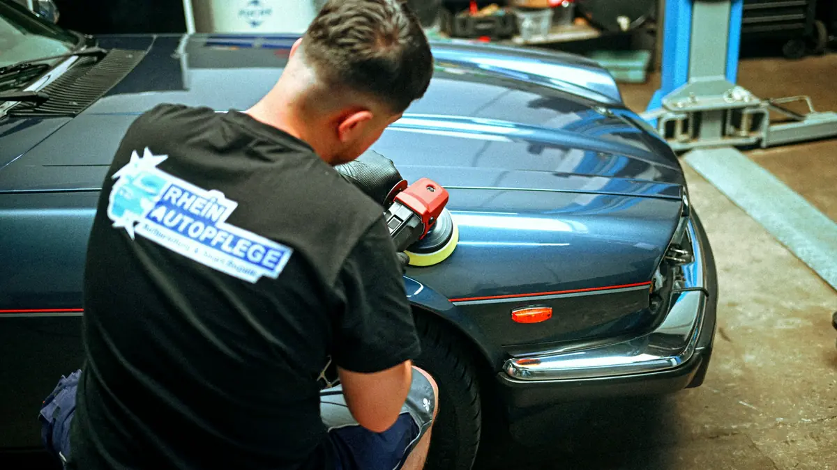 Detailer polira plavi automobil u radionici